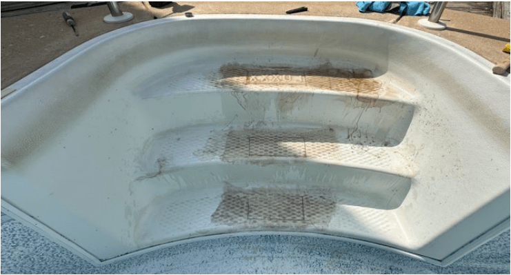 A white tub featuring a dirty bottom and steps